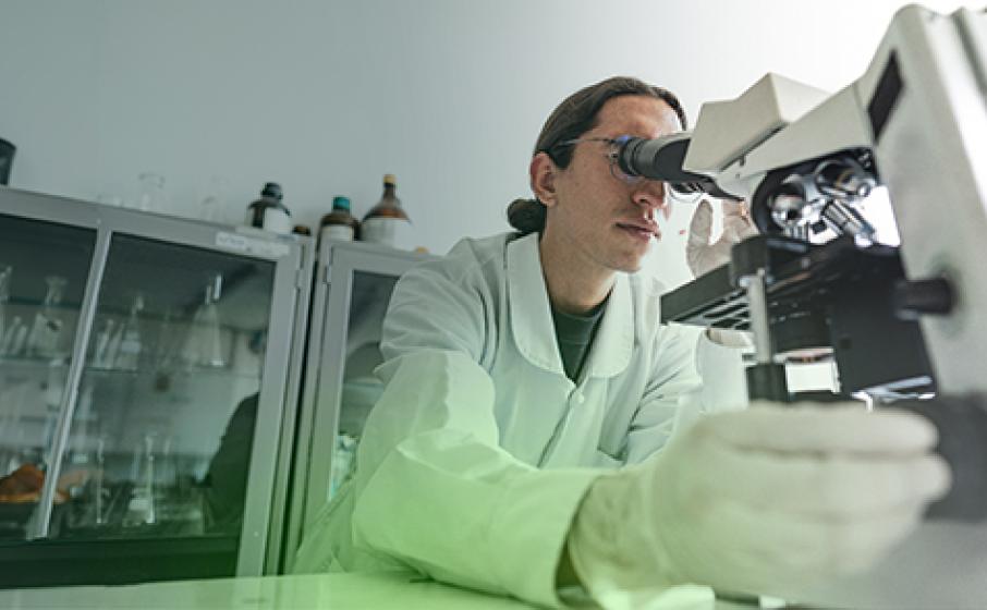 A medical technician looking through a microscope.