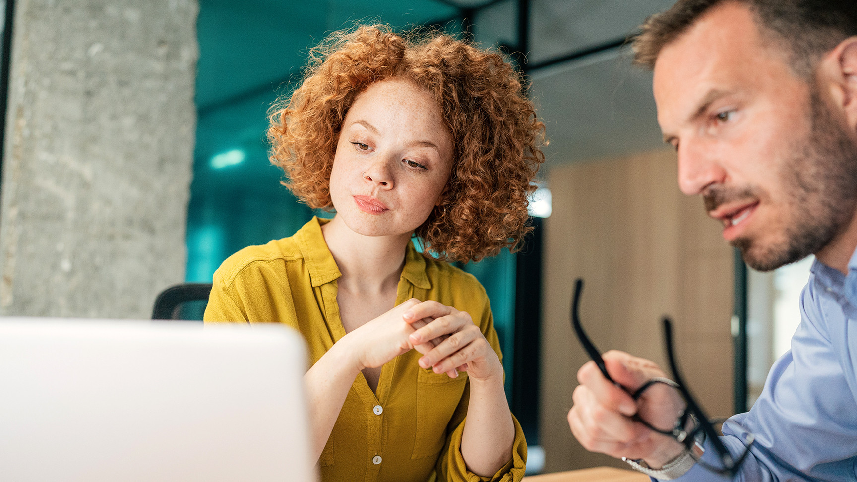 A woman and a man in a conference room staring at a computer screen