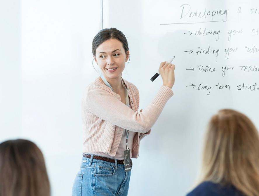 A woman instructor at a white board giving a training session to a class