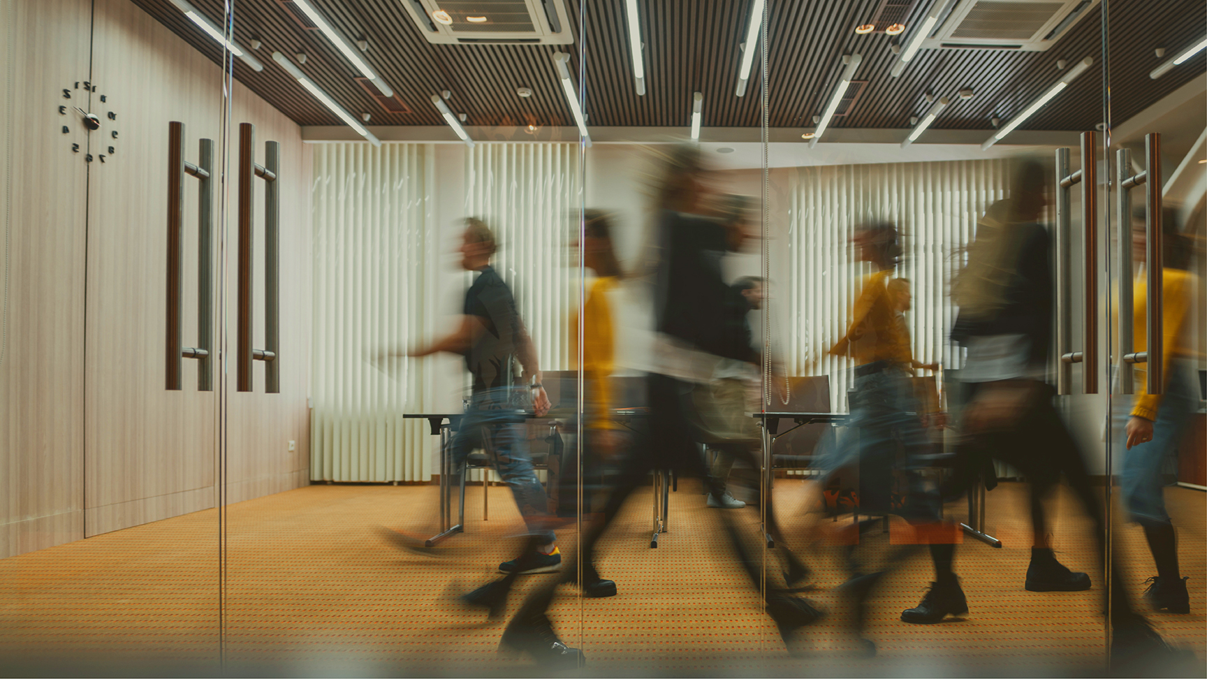 A blurred view of people walking in an open office space